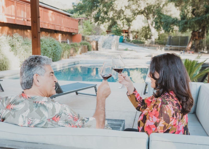 A host pouring wine for guests poolside